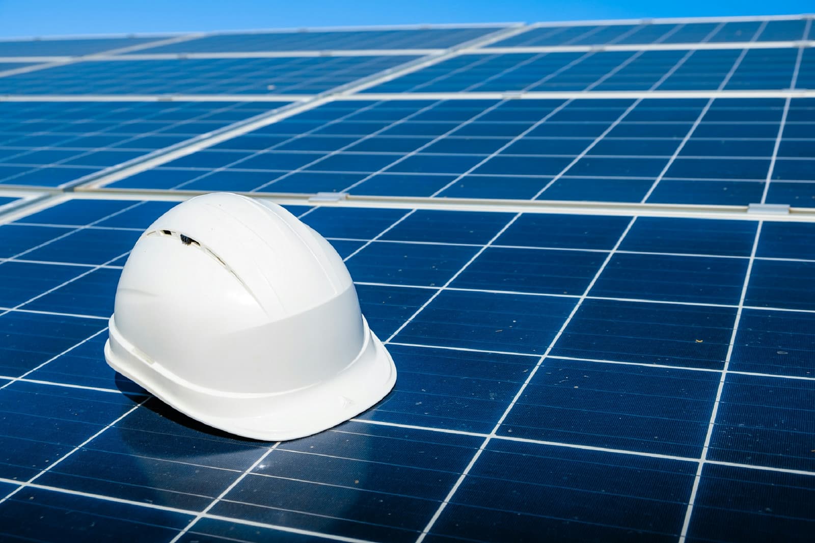 White safety helmet resting on a solar panel